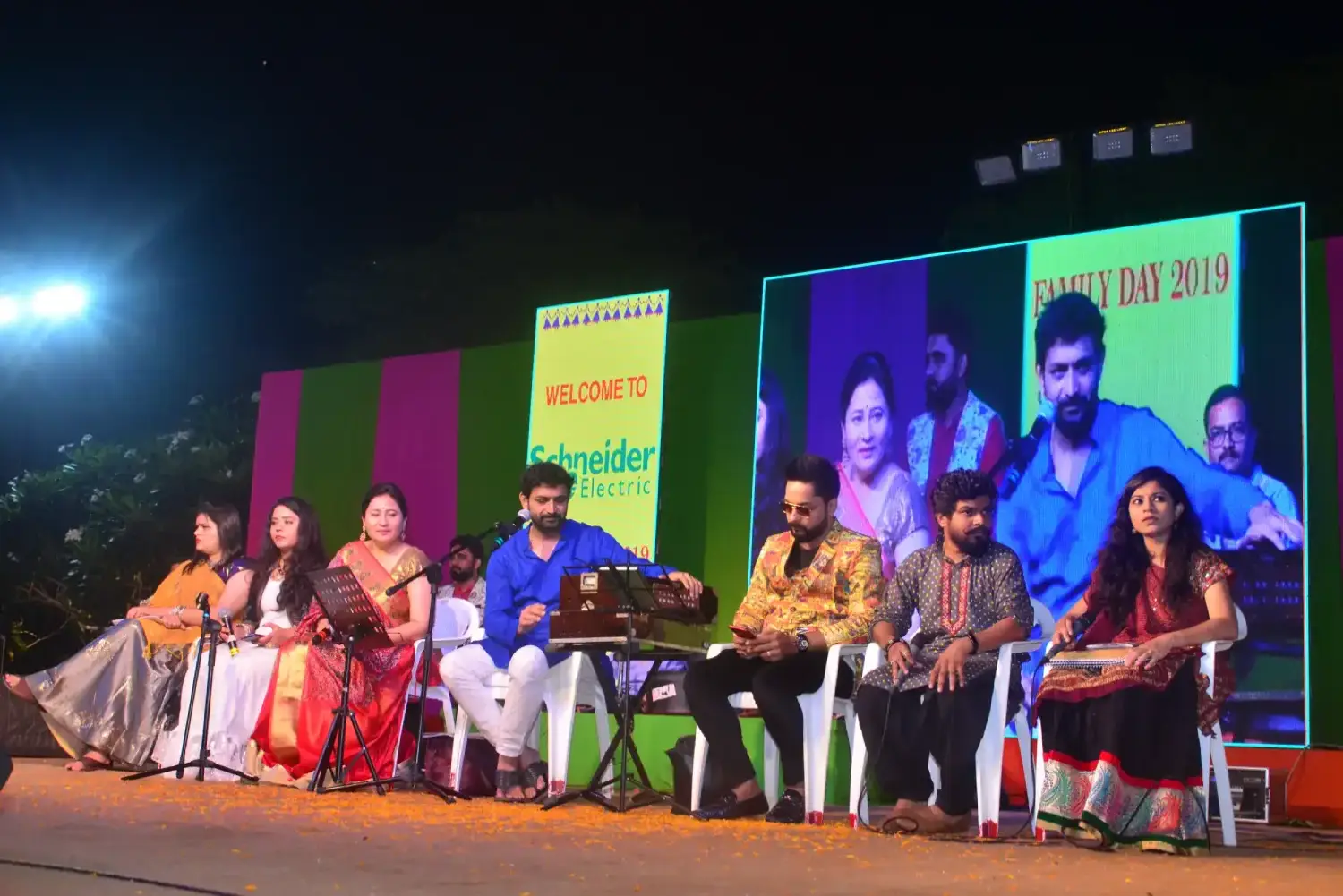 Man and woman speaking on stage at night with blue lighting